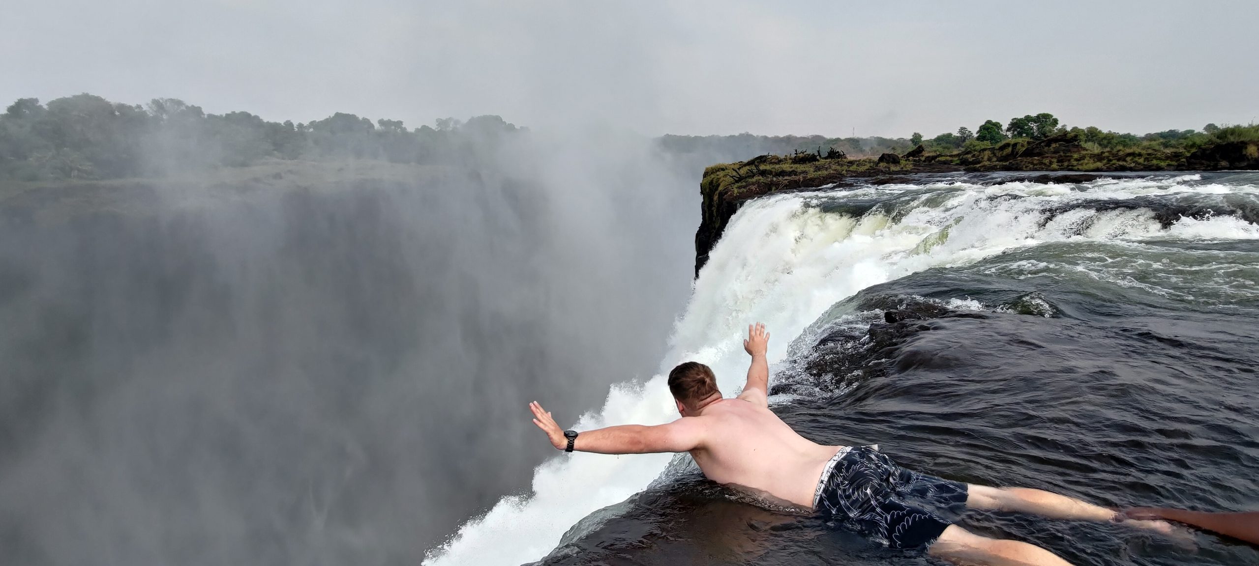 Pool am Rand des Victoria Falls mit Blick auf den Wasserfall, einzigartiges Naturerlebnis in Afrika.