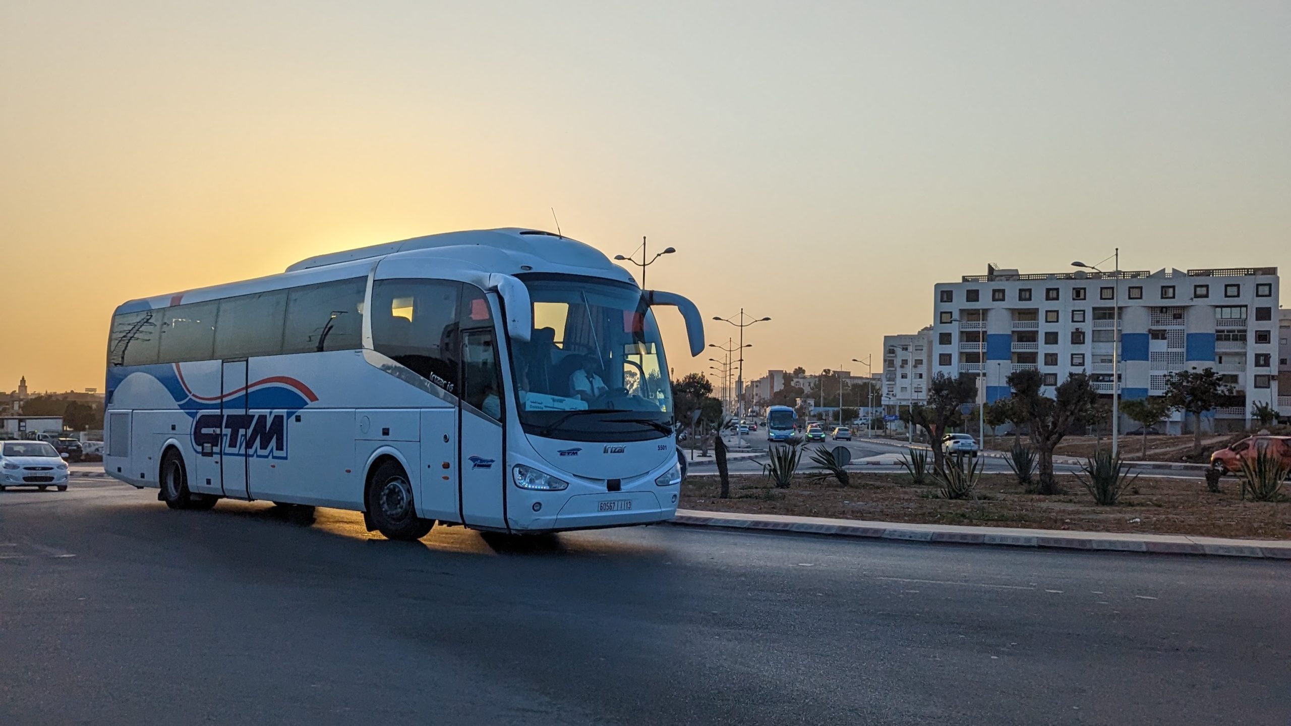 Moderner Bus auf der Straße während Sonnenuntergang auf dem Weg nach Dakhla.