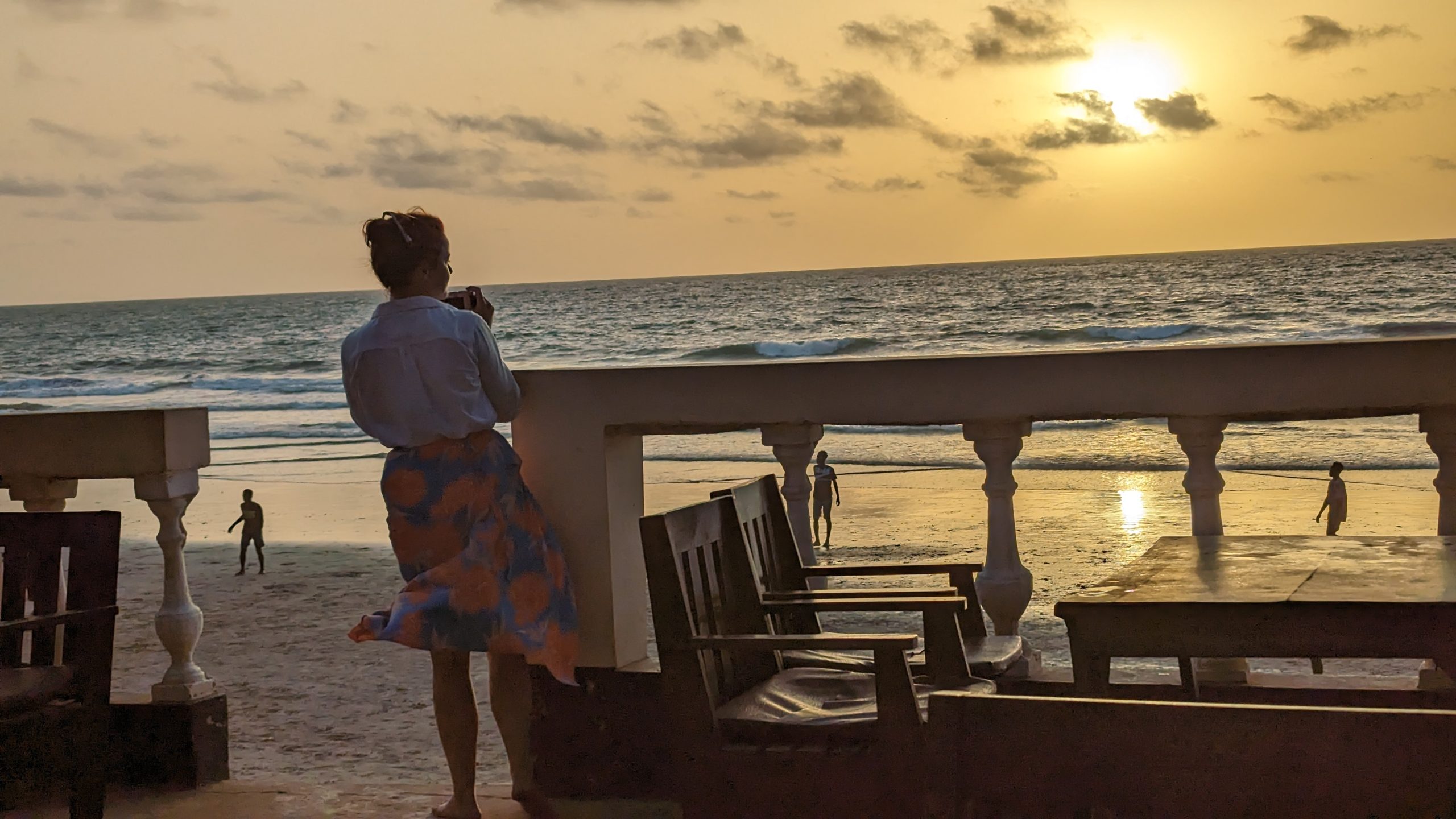 Blick auf den Strand mit Frauen und Männern beim Sonnenuntergang in Gambia.