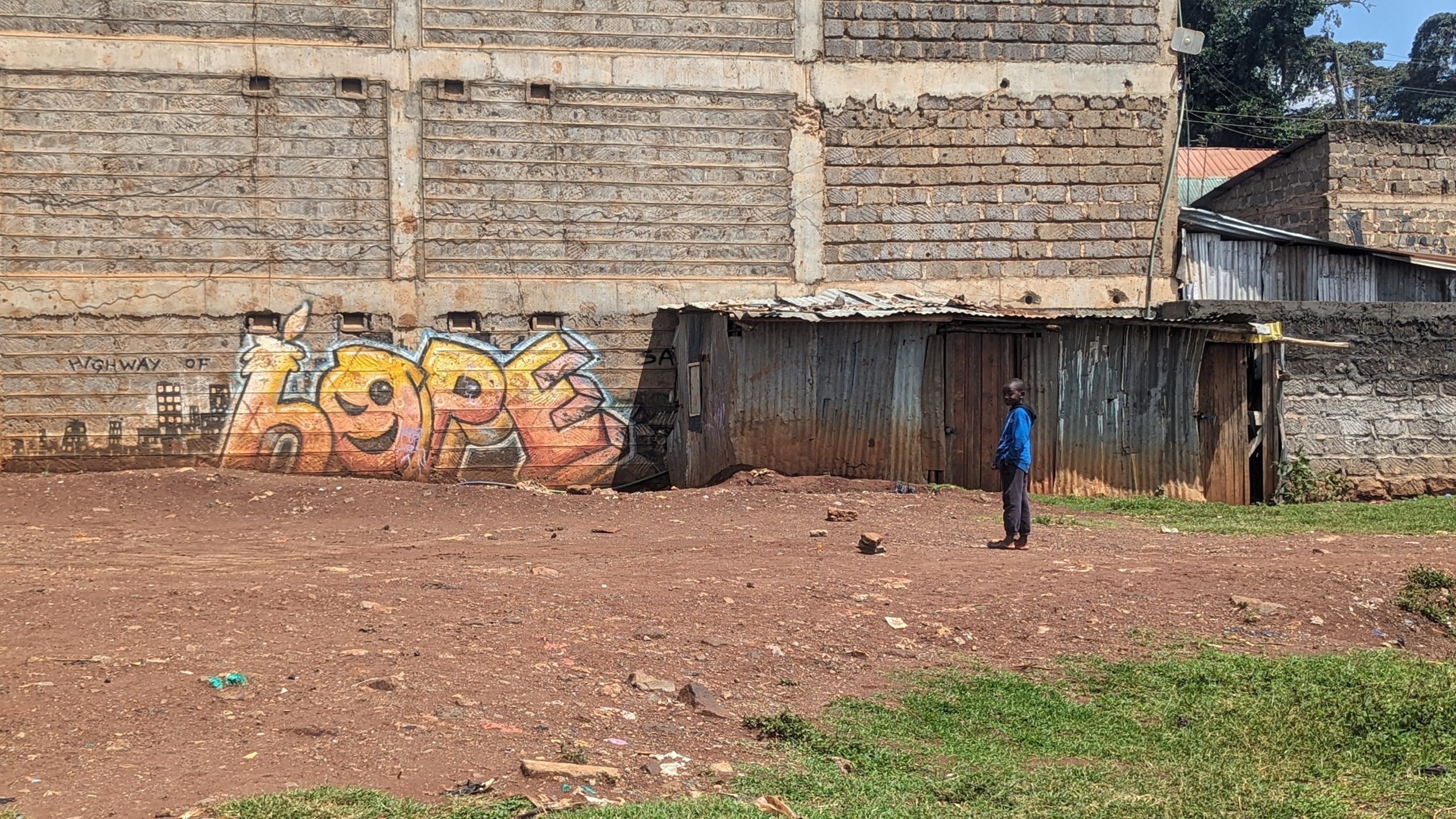 Ein Kind steht vor einer einfachen Hütte in einem armen afrikanischen Viertel.
