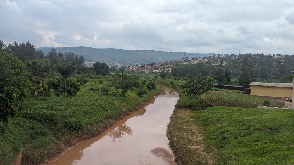 Fluss in Kigali umgeben von Hügeln und grüner Landschaft.