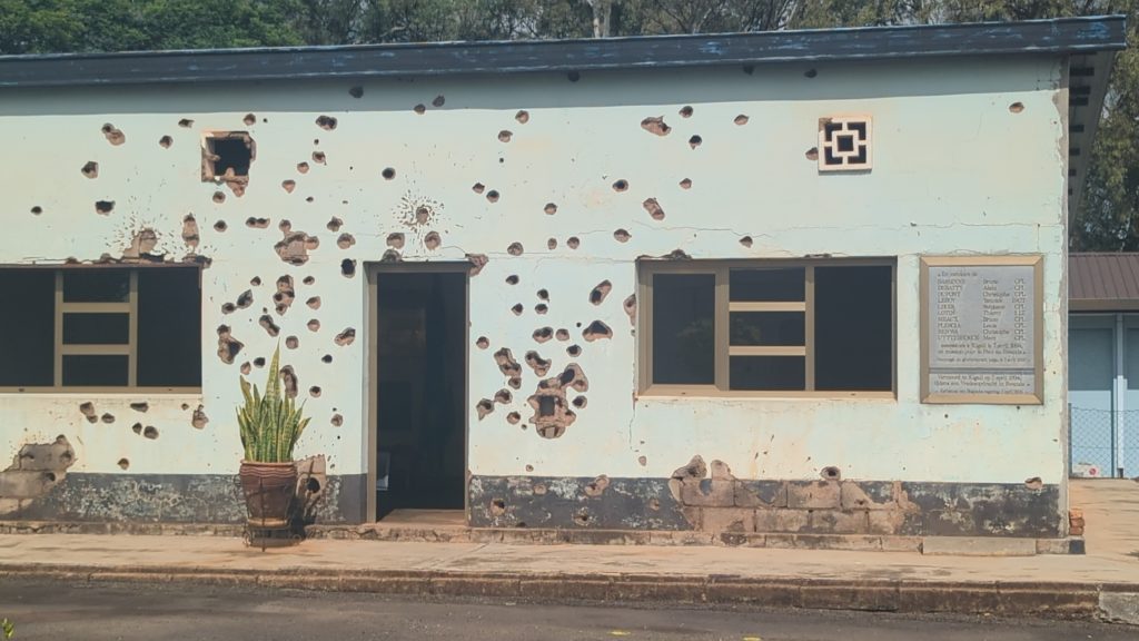 Verfallenes Gebäude in Kigali mit beschädigter Fassade und offenen Fenstern, symbolisiert die Geschi.