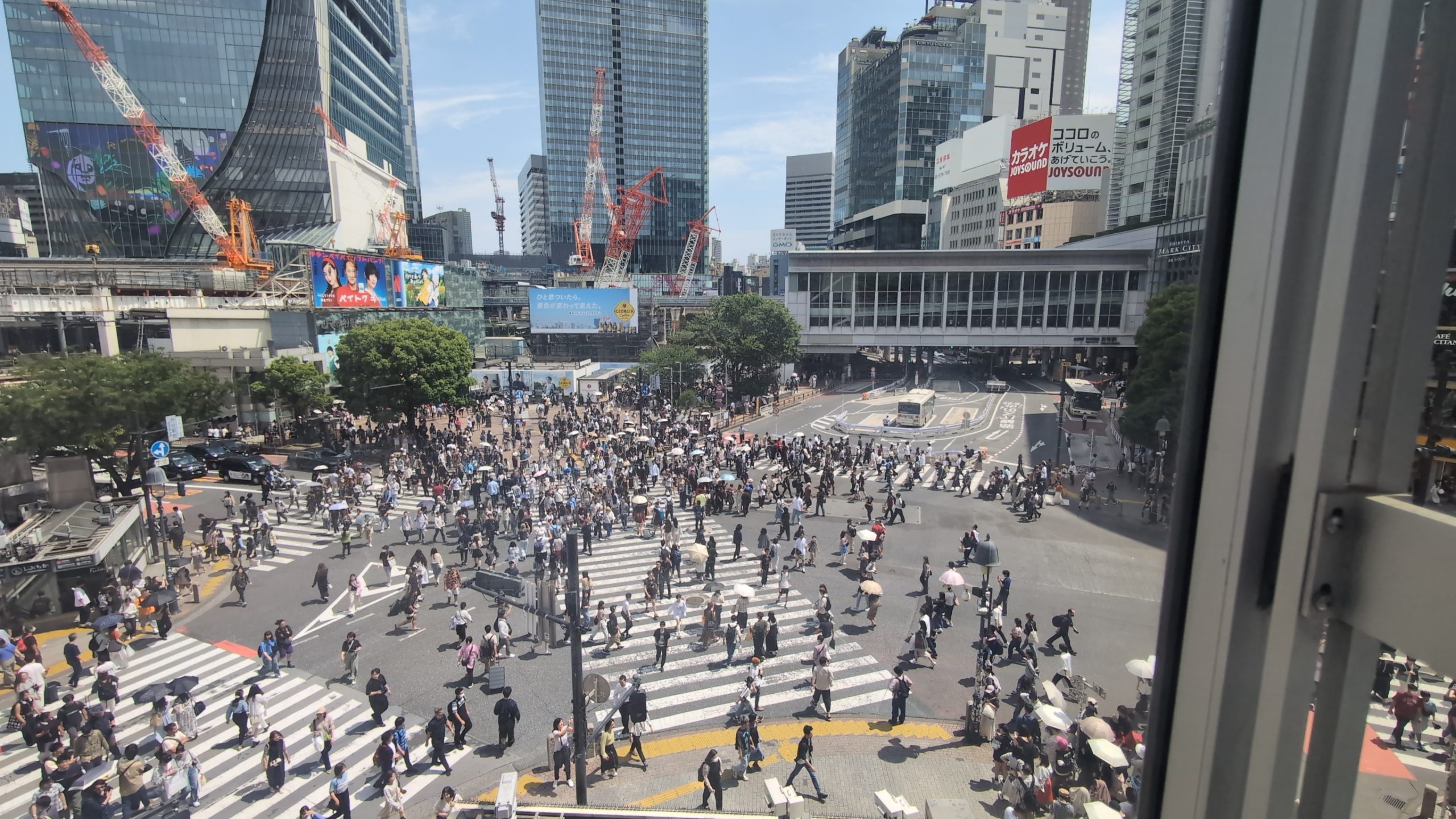 Lebendige Straßenszene in Tokio mit Menschenmengen und Hochhäusern im Hintergrund.