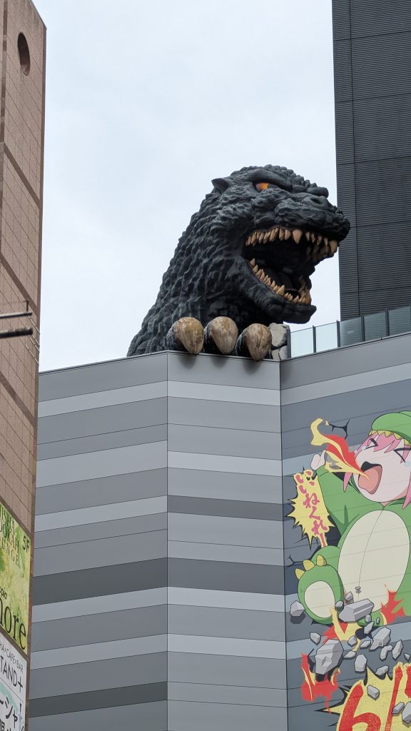 Großes Godzilla-Denkmal auf einem Gebäude in Tokio, Japan, bei bewölktem Himmel.
