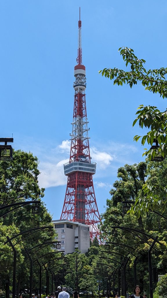 Blick auf den berühmten Fernsehturm in Tokio, umgeben von grünen Bäumen, bei klarem Himmel.