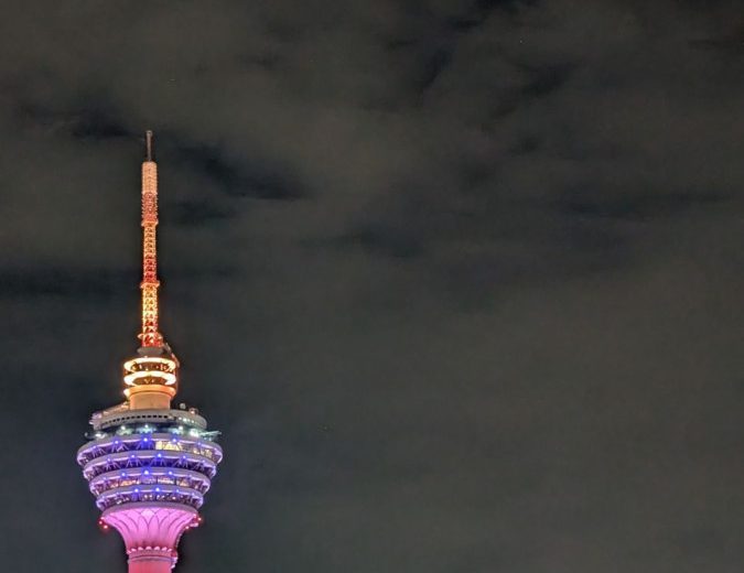Skyline von Kuala Lumpur und Singapur bei Nacht mit reflektierendem Wasser.