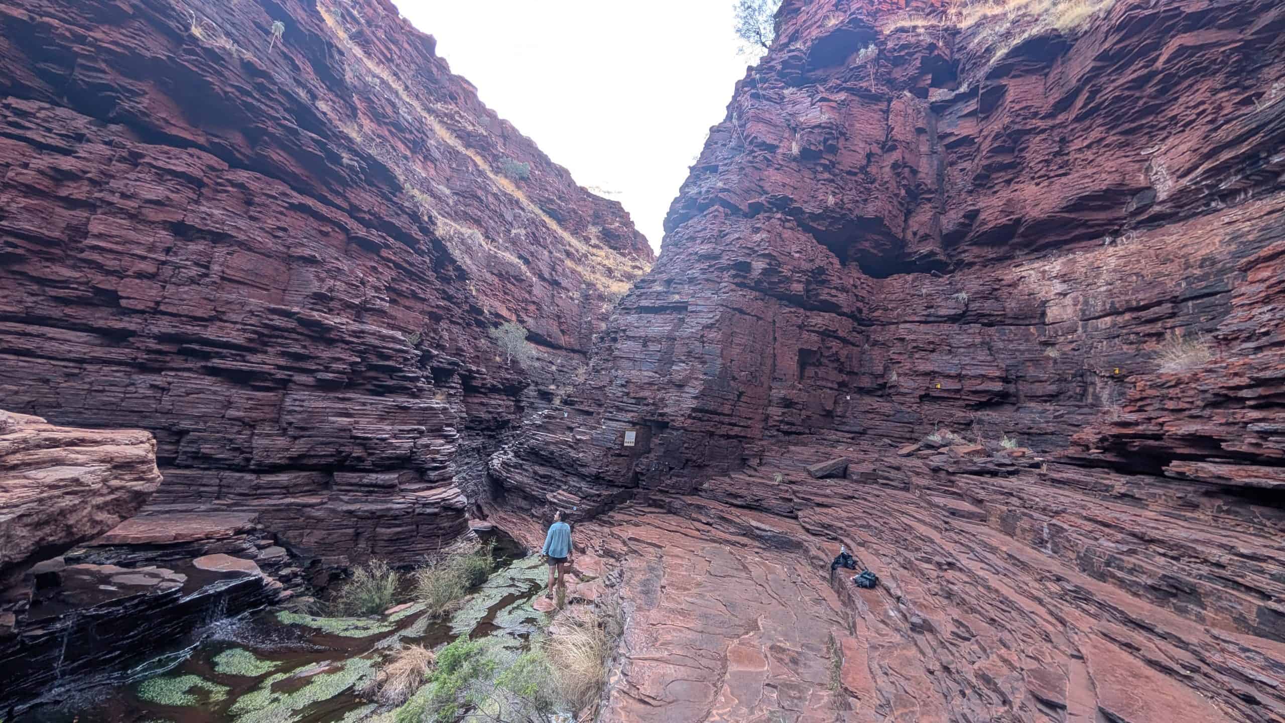 Kliff in Karijini mit Wanderer und Leitern.